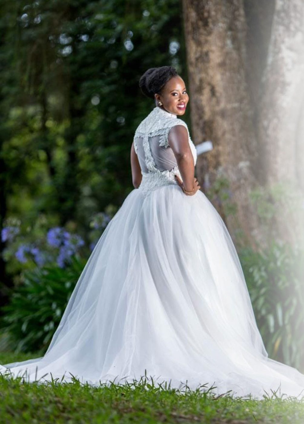 Bride in a ball gown turning to smile in a garden setting
